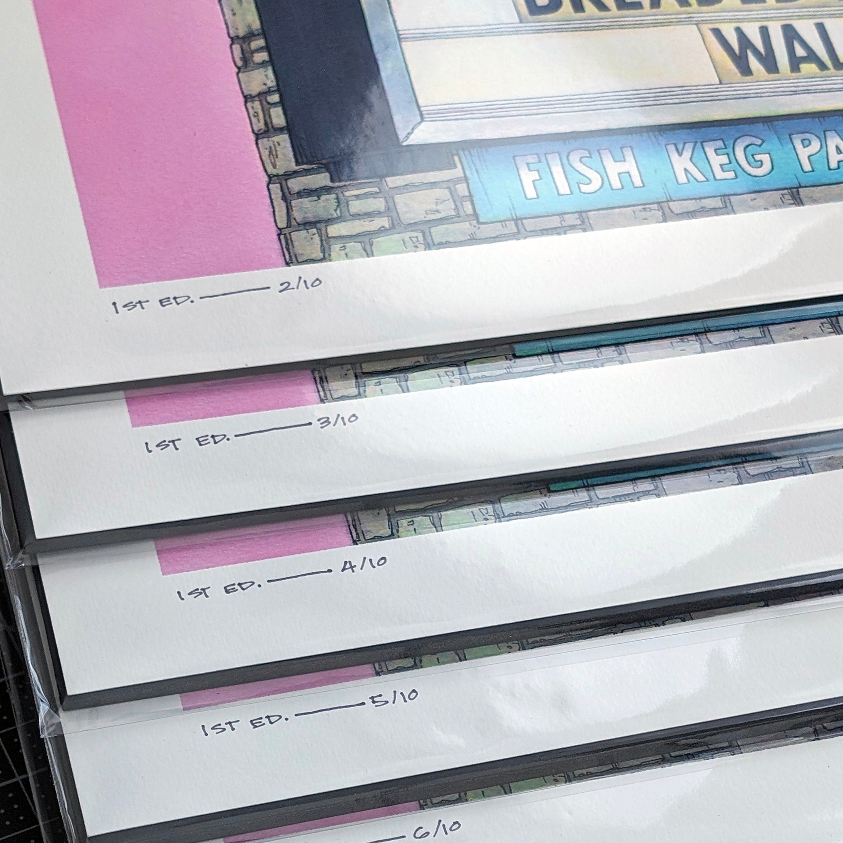 This is a photo showing a stack of hand-numbered limited editions art prints. The original artwork was created with india ink on watercolor paper by artist Katy V. Meehan. These are prints of a hand painted rendering of a vintage restaurant sign. The artwork is titled, ‘The Fish Keg’.